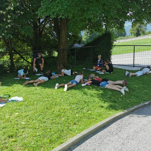SchülerInnen liegen auf der Wiese und lösen Mathematik Aufgaben