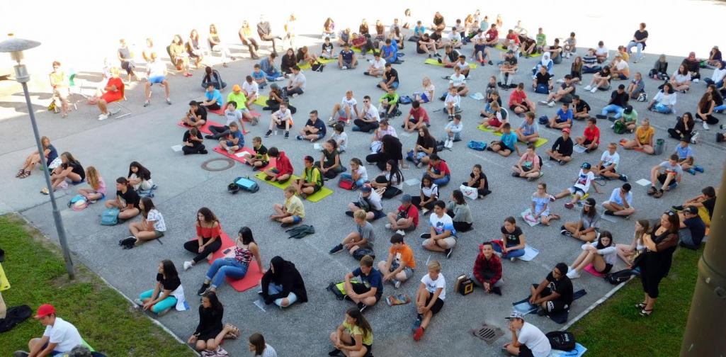 Schülerinnen und Schüler auf Parkplatz sitzend